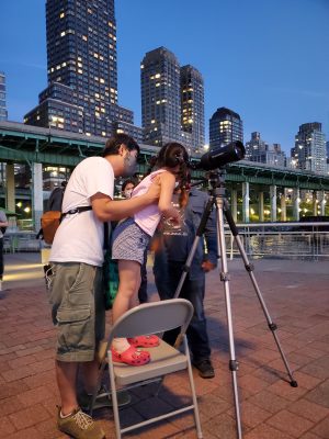 Astronomers help a child look through a telescope on the pier