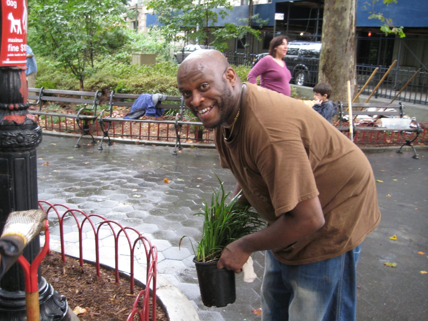 Volunteer holds plant in preparation of planting in garden