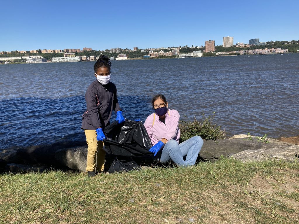 Two volunteers collect trash along the waterfront