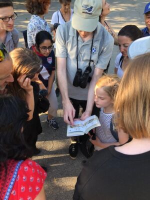 bird watchers show children a book about the species that live in Riverside Park