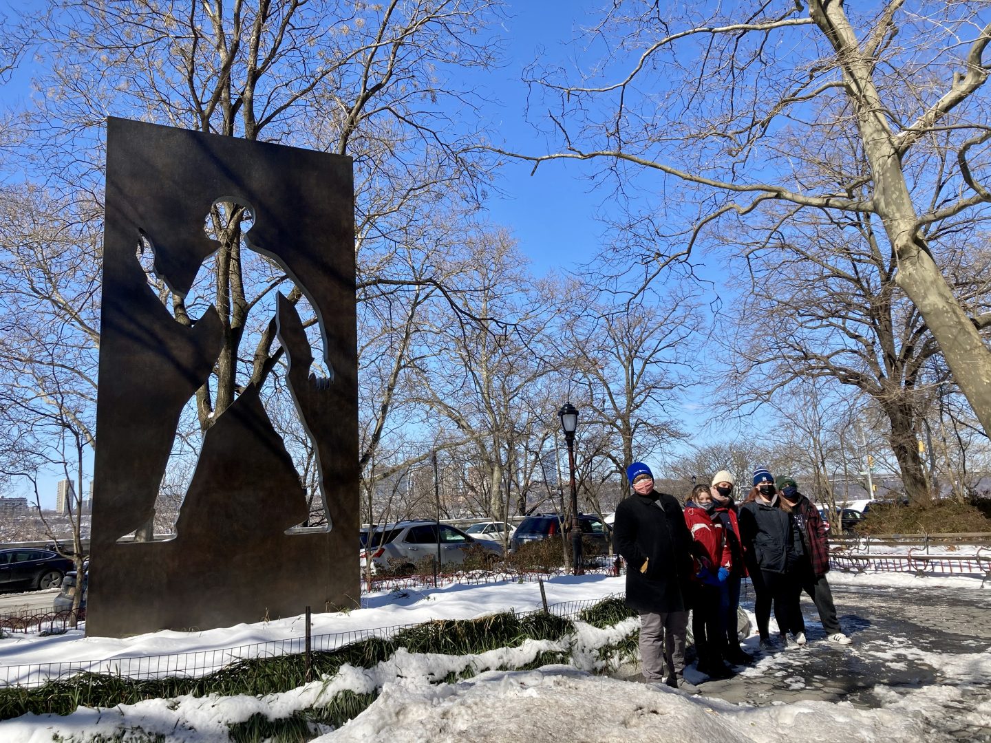 A group of volunteers smile in front of the Ralph Ellison Memorial in the snow